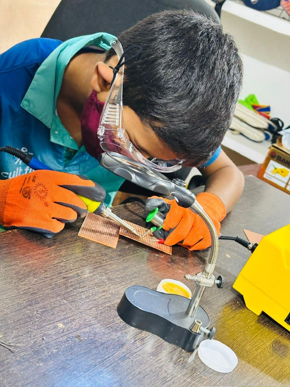 Vanij soldering a circuit board for the smart blind stick
